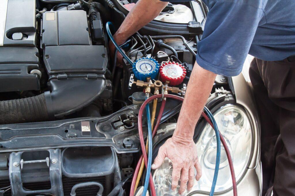 Mechanic with manometer inspecting auto vehicle air condition co
